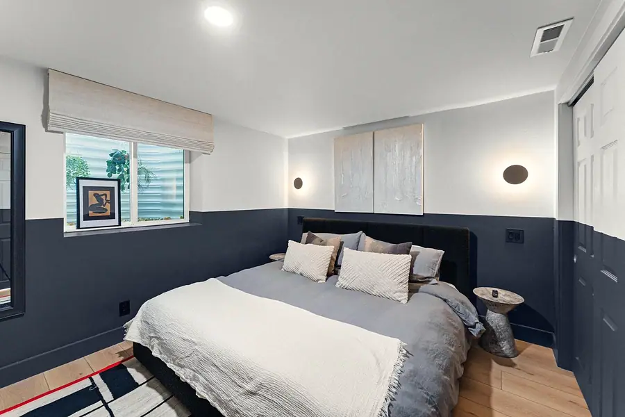 Midway bedroom with navy half-wall paint, gray bedding, and dual wall sconces