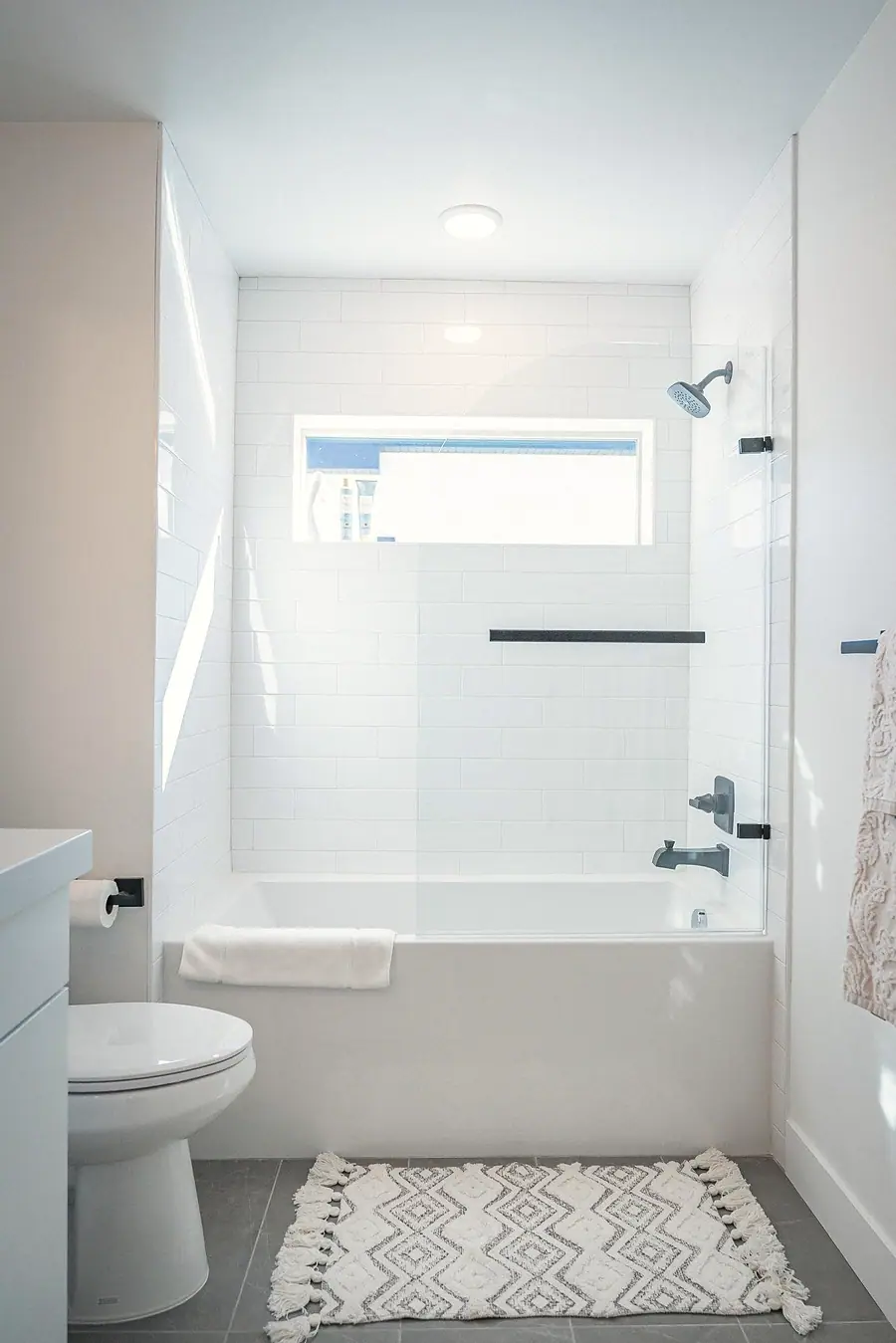 Silver Creek tub and shower with white subway tile, matte black fixtures, and patterned rug