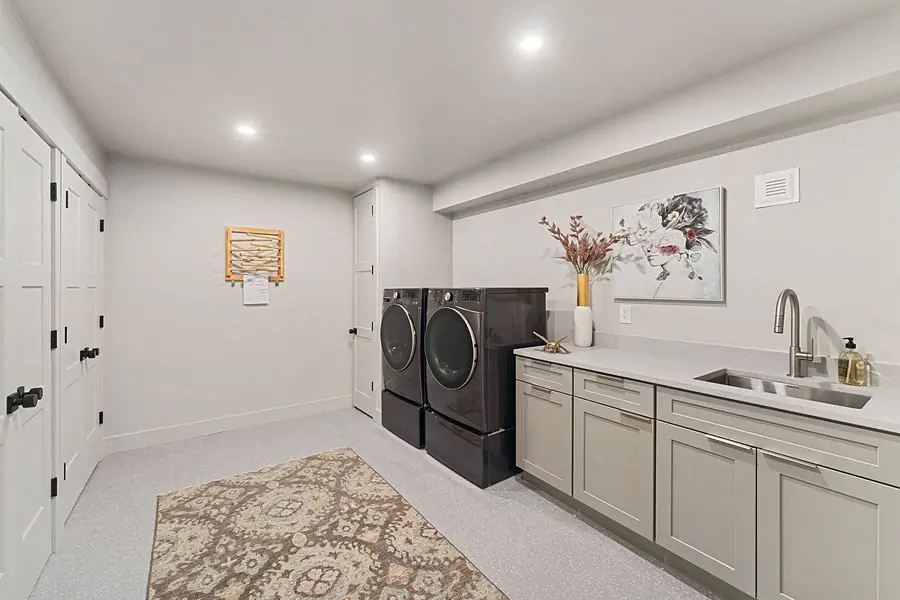 Matterhorn Hygge House laundry room with gray cabinetry, utility sink, and side-by-side washer dryer