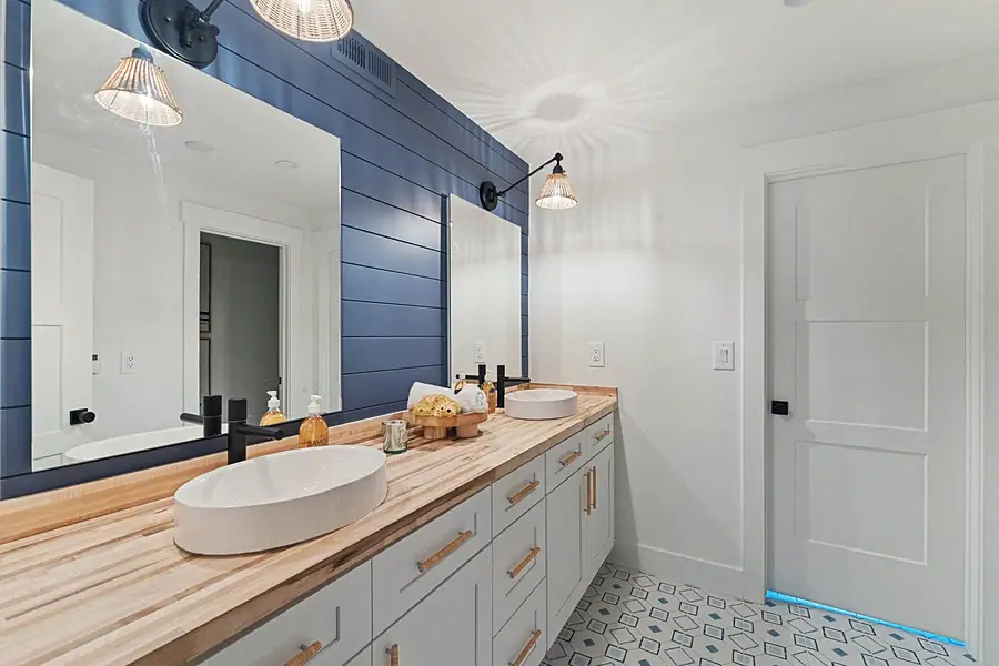 Matterhorn Hygge House bath with blue shiplap wall, wood counter, and dual vessel sinks