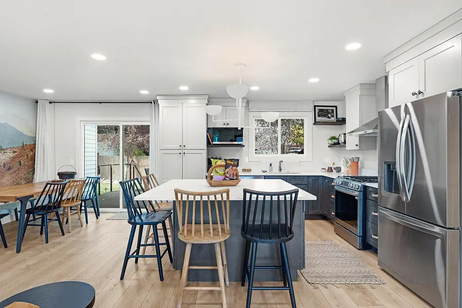 Midway kitchen and dining area with large island, mixed wood chairs, and mountain mural