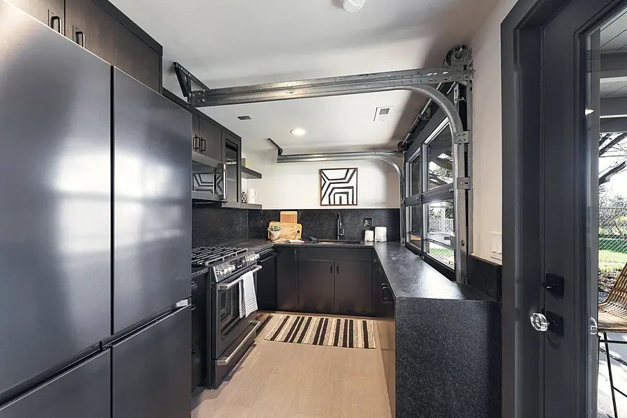 Fairway House kitchen with stainless appliances, dark cabinetry, and glass garage door