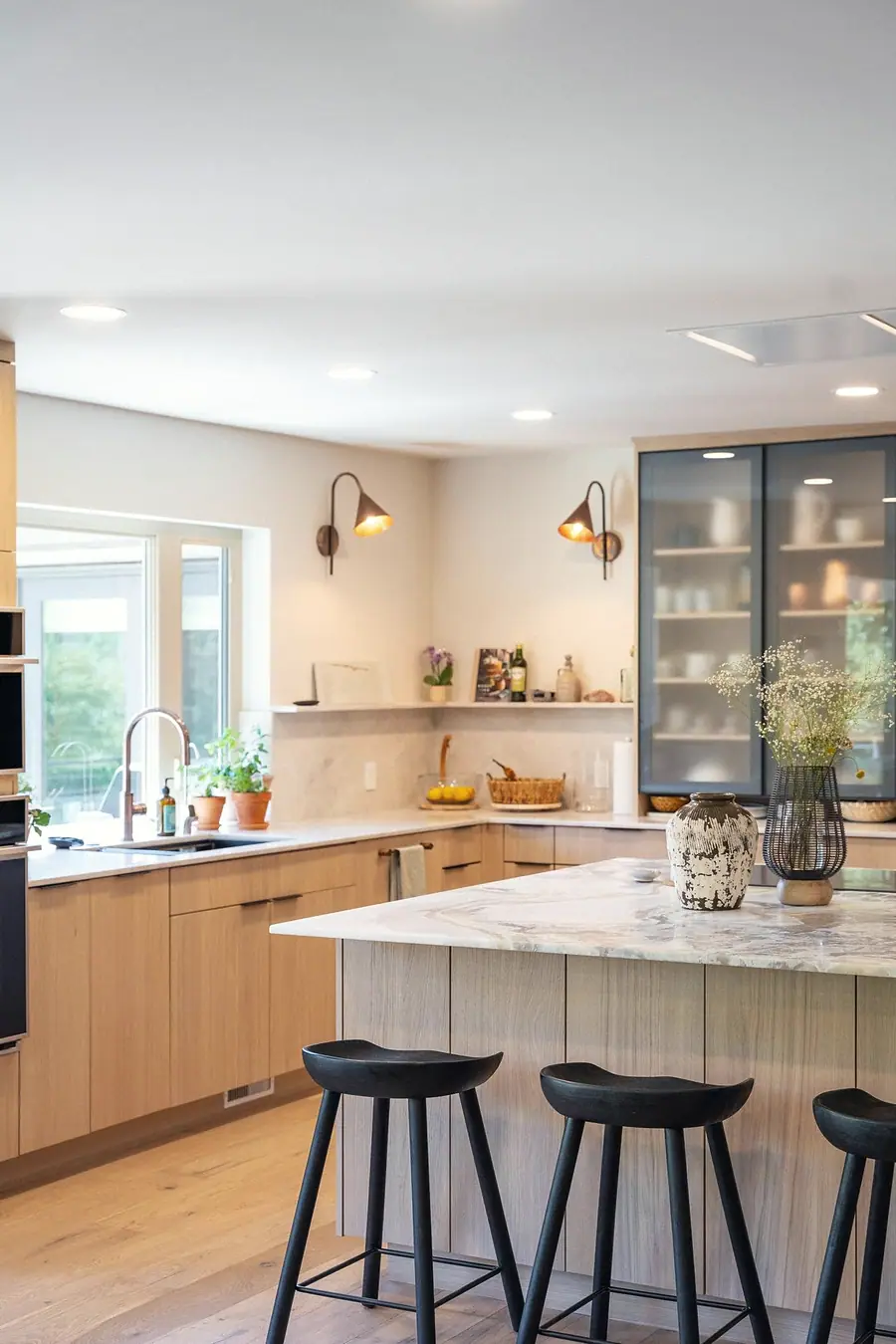Elysium kitchen island detail with black stools, ceramic vase, and glass-front cabinetry