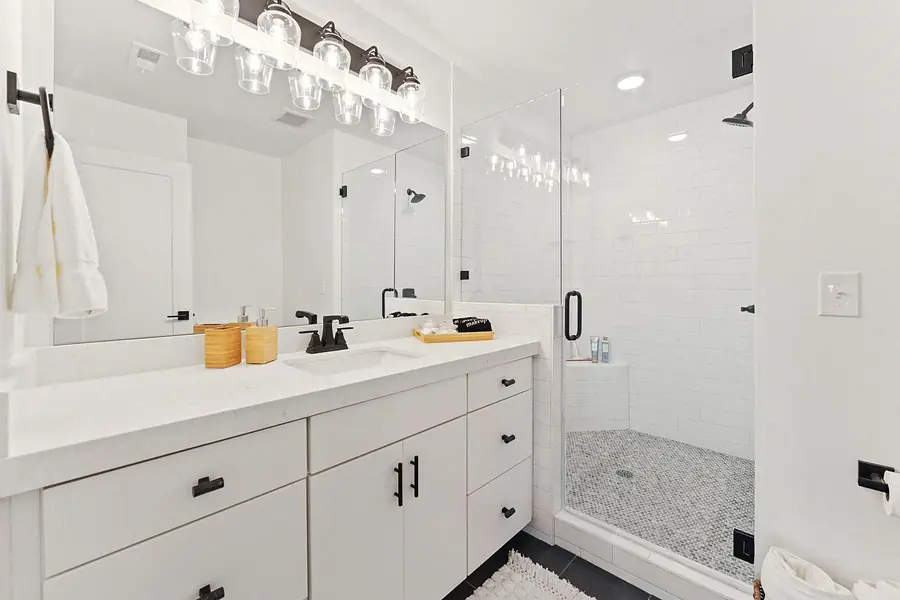 Silver Creek full bathroom with white vanity, glass shower, and pebble floor