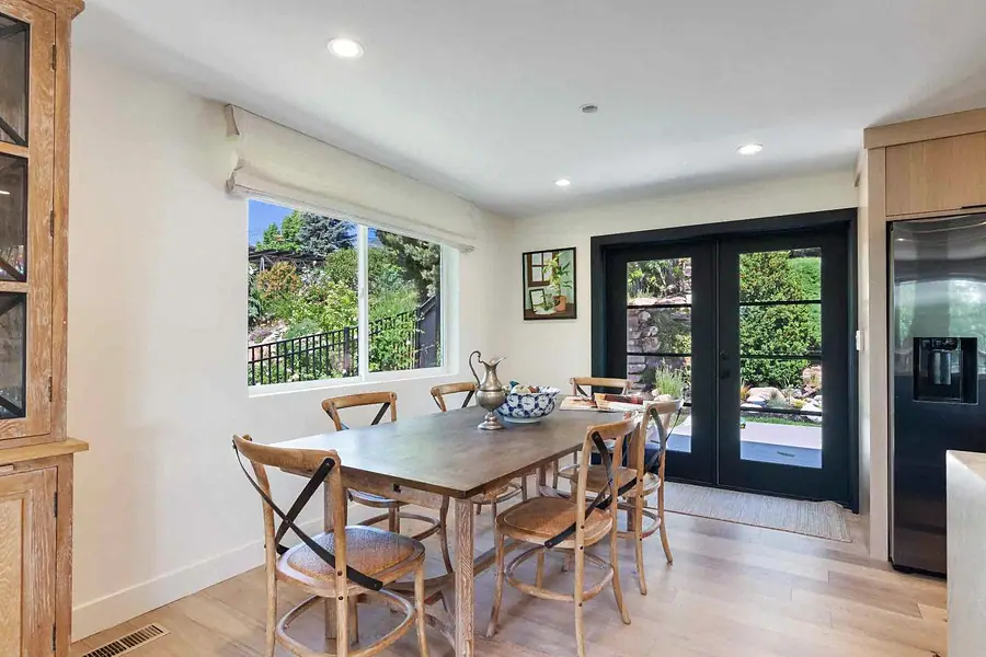 Wallace Project dining area with wood table, French doors, and garden view