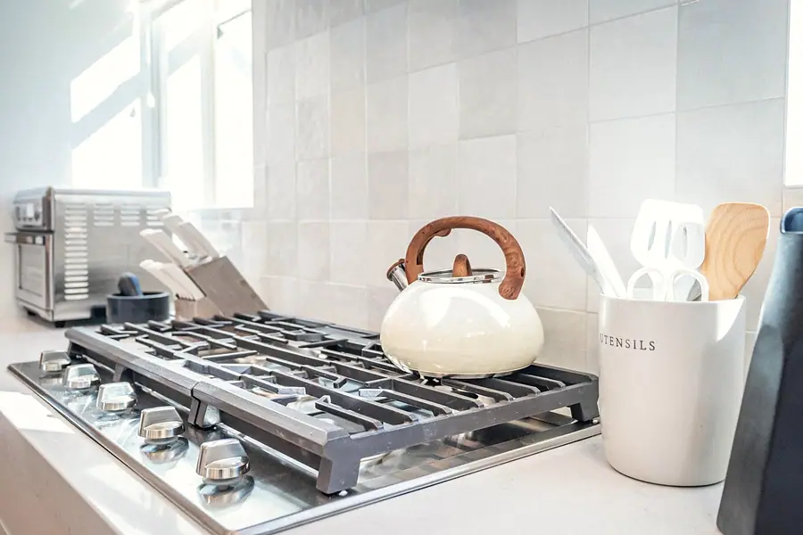 Silver Creek kitchen gas range with cream kettle, utensil crock, and white tile backsplash