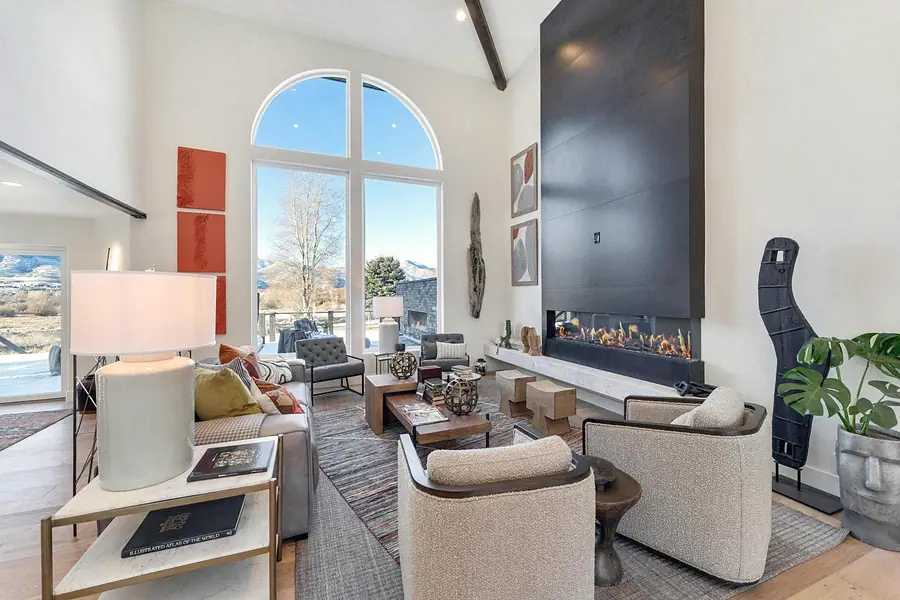Great room with arched windows, linear fireplace, and mountain views