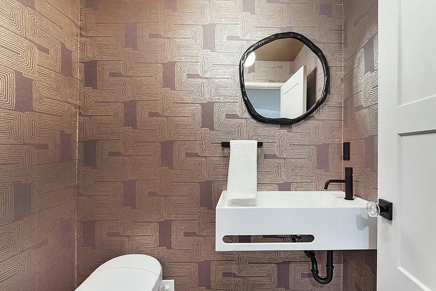 Fairway House powder room with geometric wallpaper, floating sink, and organic mirror