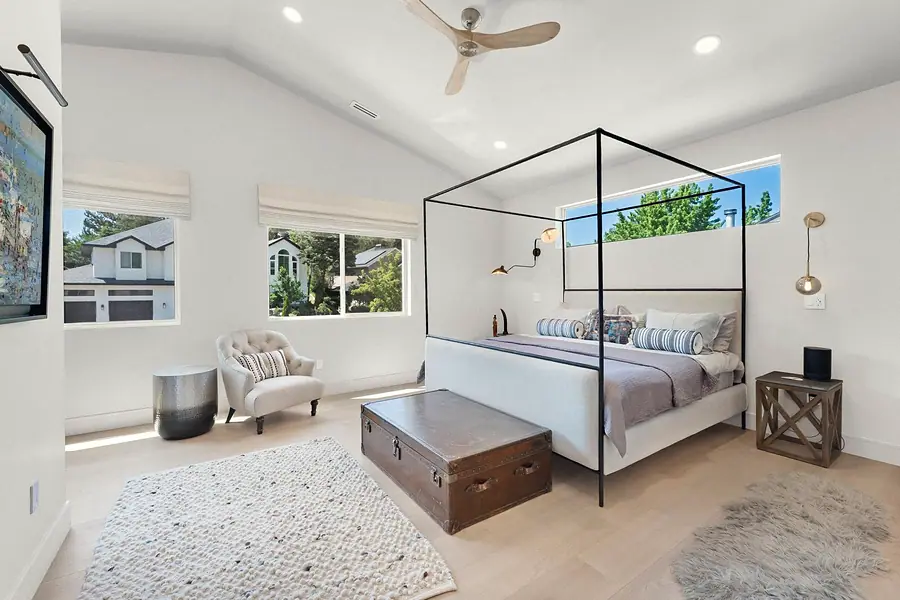 Elysium primary bedroom with black canopy bed, trunk bench, and mountain windows