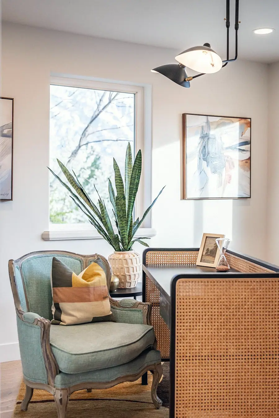 Grand Vista office corner with seafoam chair, snake plant, and cane desk detail