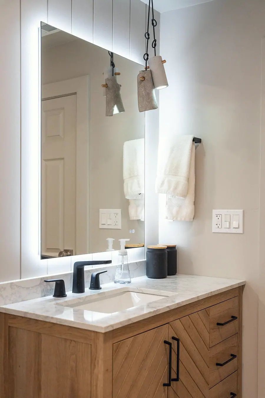 Midway vanity with marble top, matte black fixtures, and concrete pendant lights
