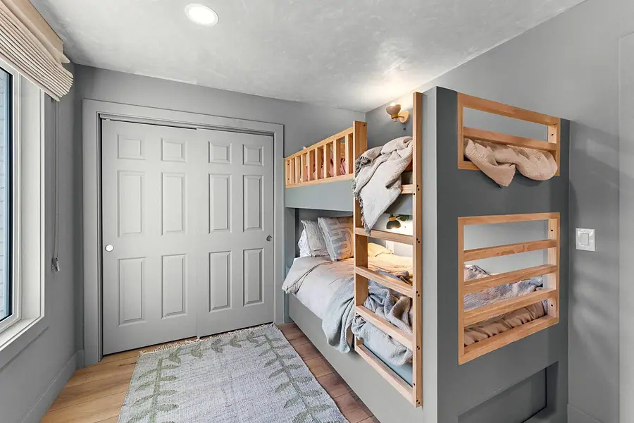 Midway bunk room with built-in wood bunks, gray closet doors, and leaf-pattern rug