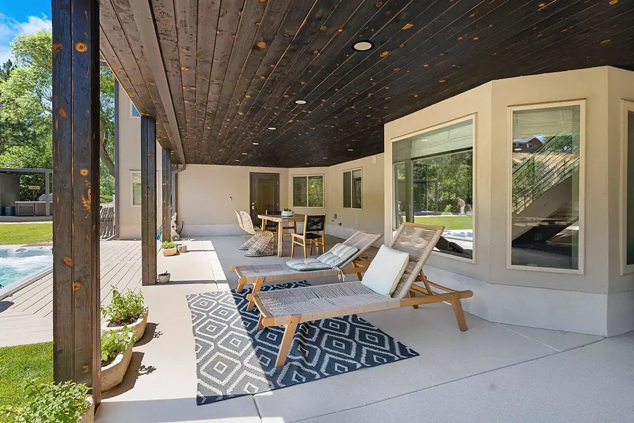 Elysium covered patio lounge with chaise chairs and dark wood ceiling