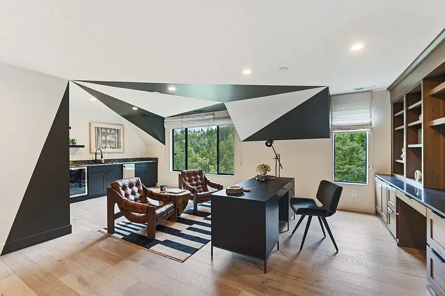 Matterhorn Hygge House office loft with leather lounge chairs, black desk, and geometric ceiling