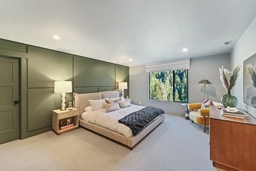 Matterhorn Hygge House primary bedroom with sage paneled wall, platform bed, and forest views