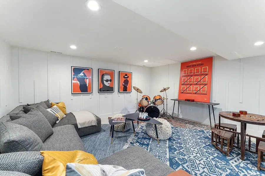 Basement lounge with sectional seating, drums, and West Side Story art