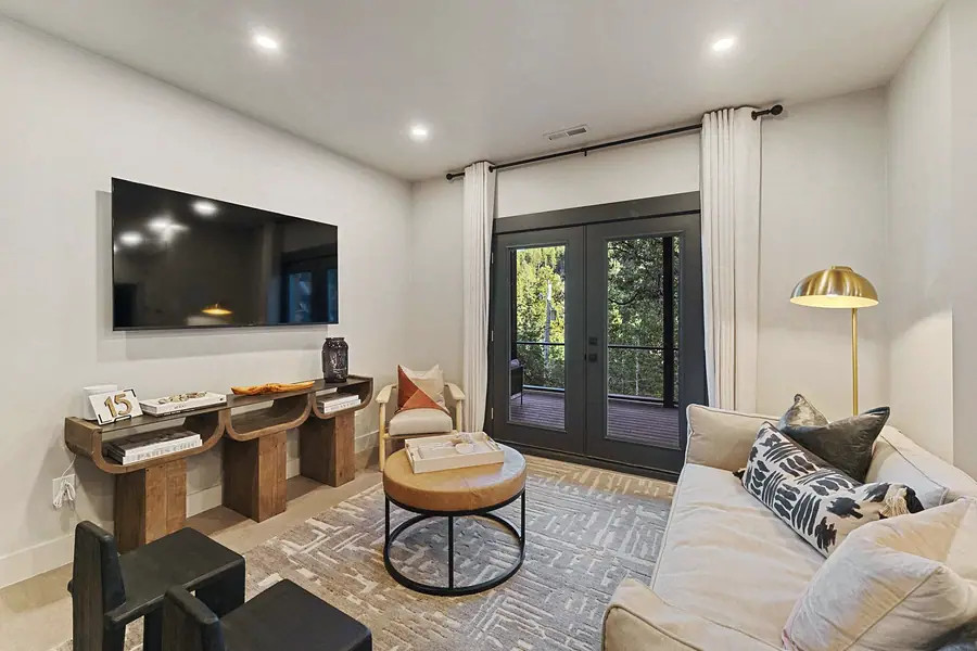 Matterhorn Hygge House media lounge with wall TV, sculptural wood console, and French doors to the deck