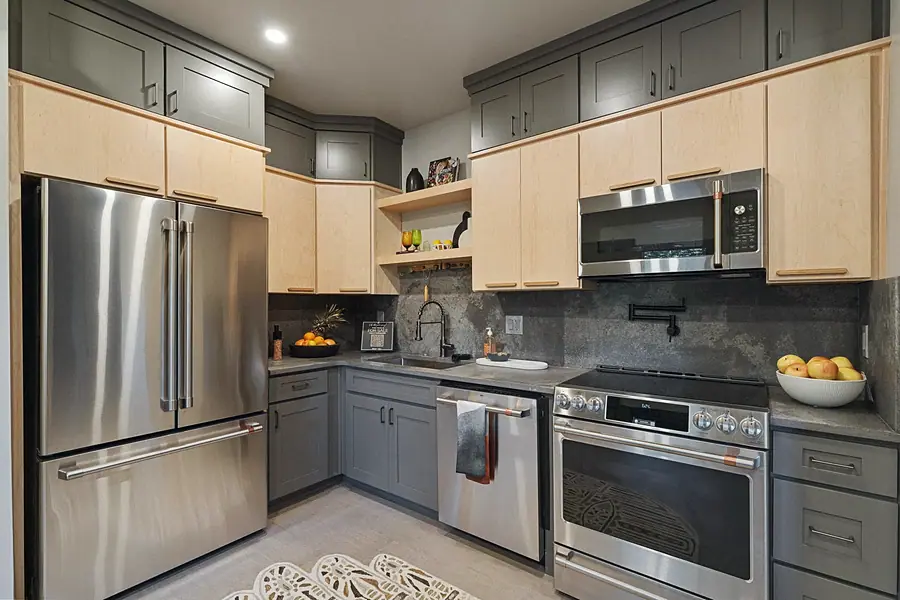 Matterhorn Hygge House kitchen range wall with maple uppers, gray lowers, and stainless appliances