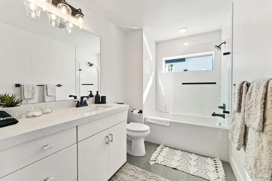 Silver Creek bathroom with white vanity, glass tub enclosure, and gray floor tile