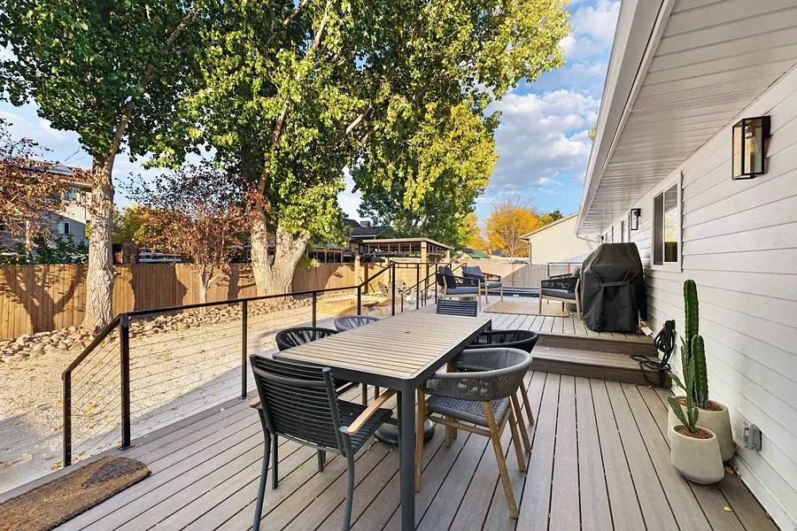 Midway deck dining table with rope chairs, cable rail, and mature trees beyond