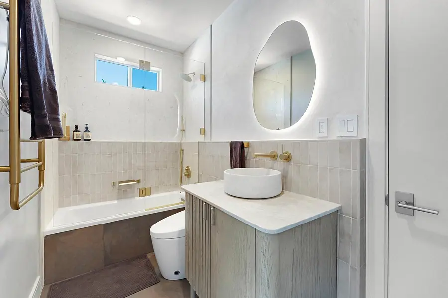 Elysium bath with organic lit mirror, vessel sink, and brass fixtures