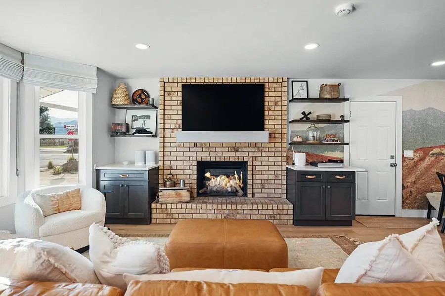 Midway living room fireplace with TV, leather seating, and mountain mural wall