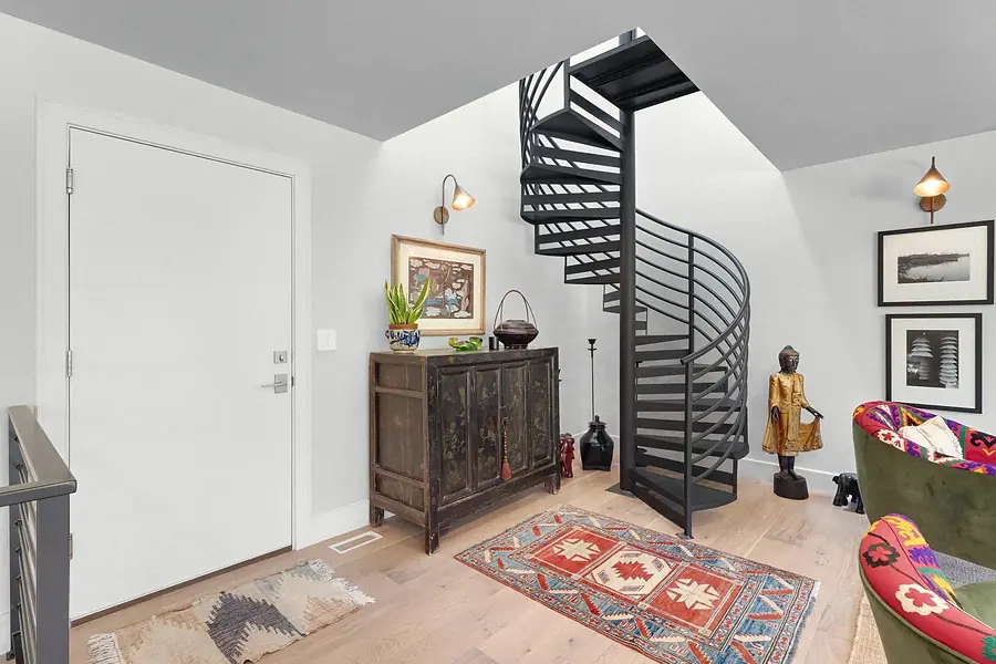 Elysium hall with black spiral staircase, antique cabinet, and Persian rug