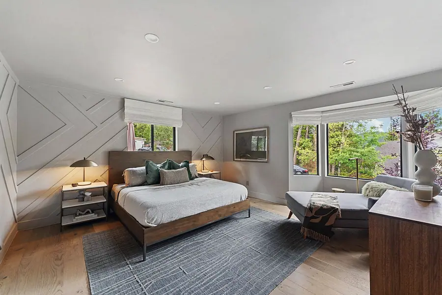 Matterhorn Hygge House bedroom with geometric wall molding, wood bed, and forest windows