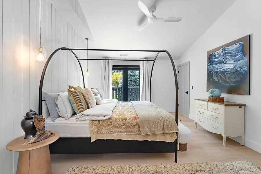 Little Gem primary bedroom with black canopy bed, pendant lights, and balcony doors