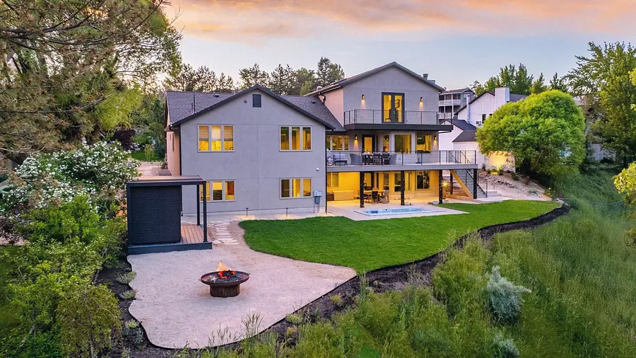 Elysium backyard at dusk with fire pit, lawn, hot tub, and multi-level decks glowing