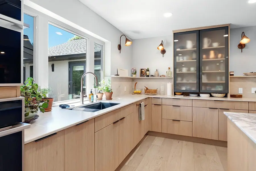 Elysium kitchen sink corner with light oak cabinets, glass display cabinet, and garden window
