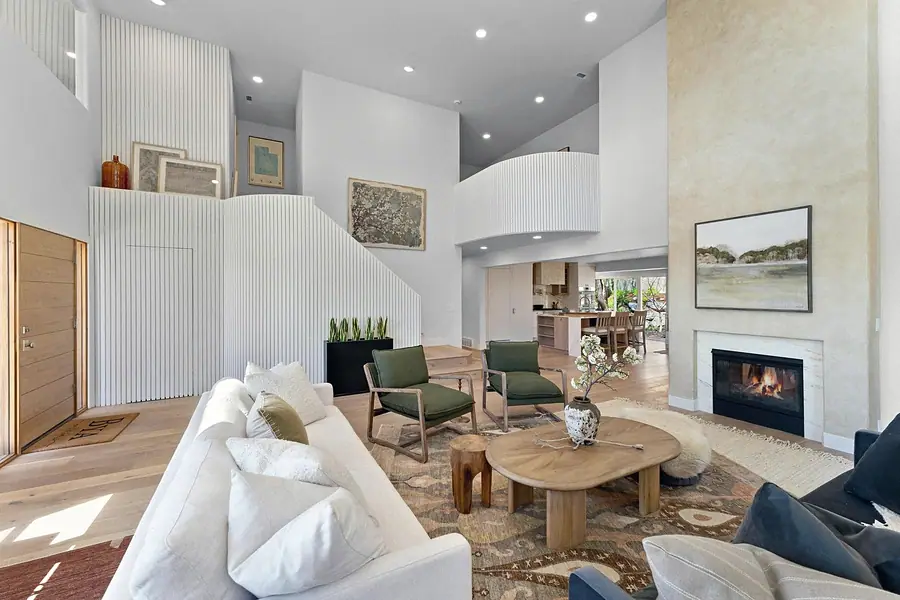 Grand Vista living room toward entry with fluted stair wall and green chairs