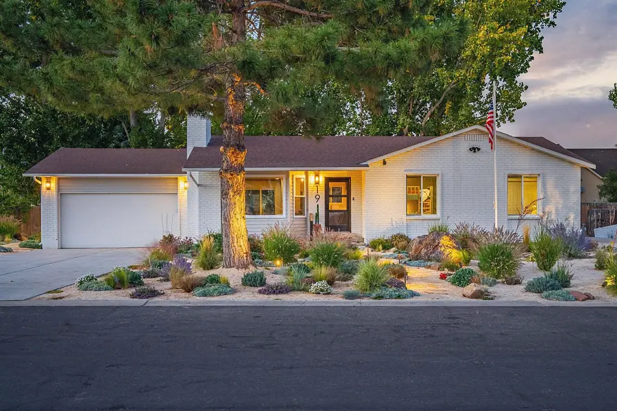 Midway vacation home exterior at dusk with white brick facade, garage, and xeriscape garden