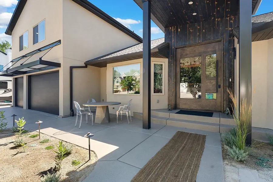 Elysium front entry with wood double doors, black steel columns, and courtyard seating