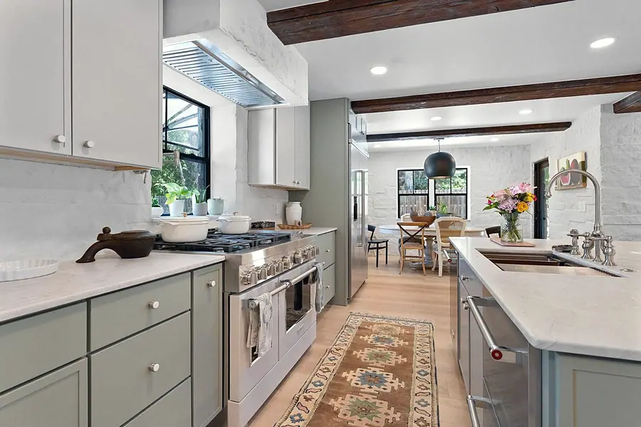 Little Gem kitchen with sage cabinets, marble counters, range, and dining beyond
