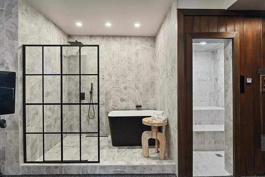 Matterhorn Hygge House spa bath with black-frame glass shower, freestanding tub, and sauna entry