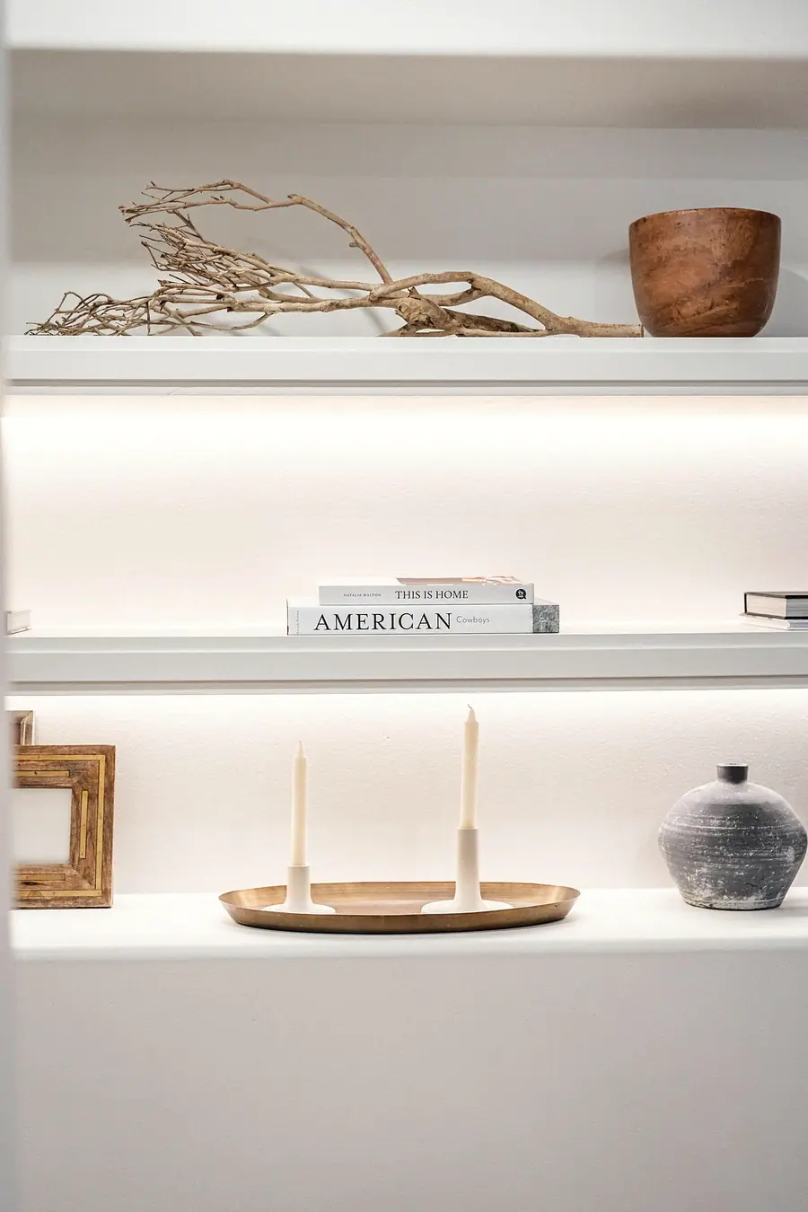 Grand Vista built-in shelves with driftwood, books, and brass candle tray