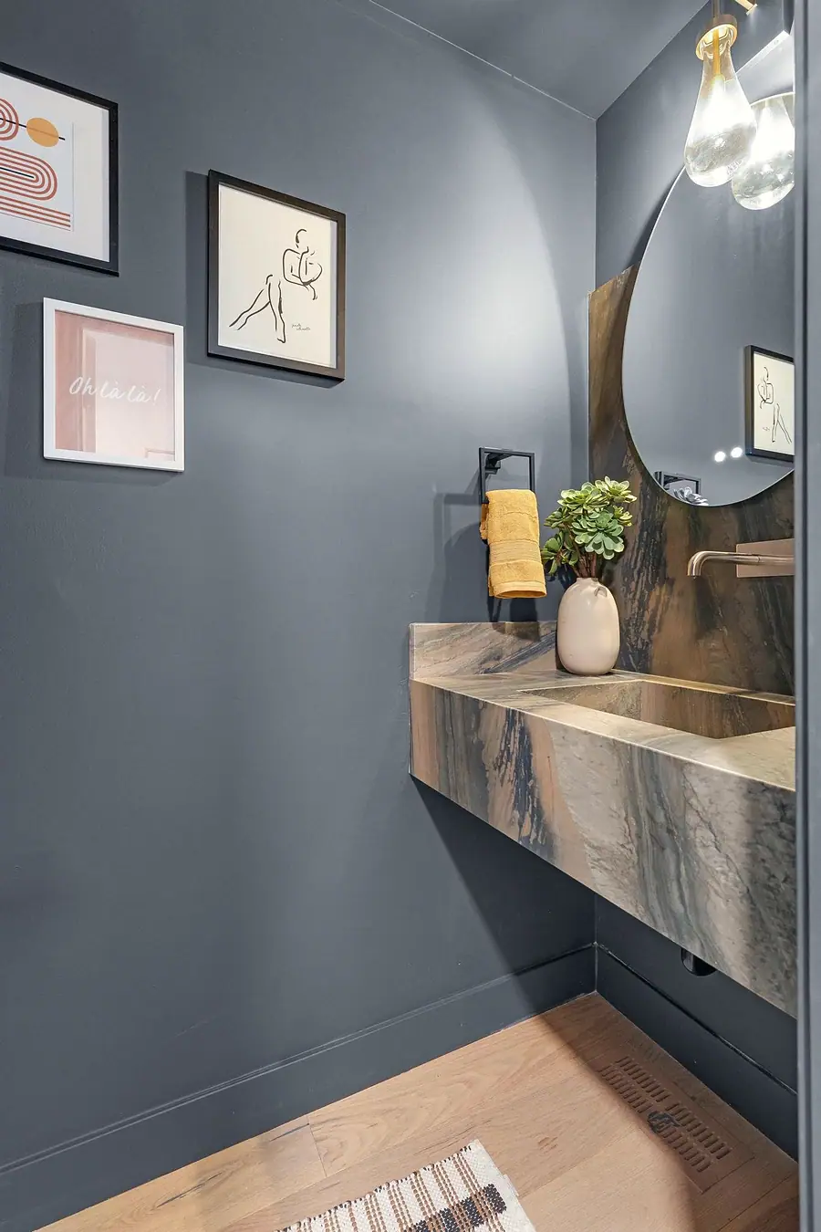 Grand Vista powder room with charcoal walls, stone floating sink, and round mirror