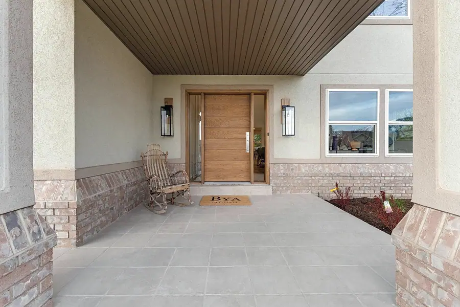 Grand Vista covered entry with wood front door and rocking chair