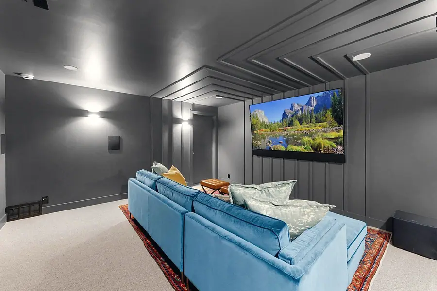 Grand Vista media room with blue velvet sectional, large screen, and charcoal paneled walls