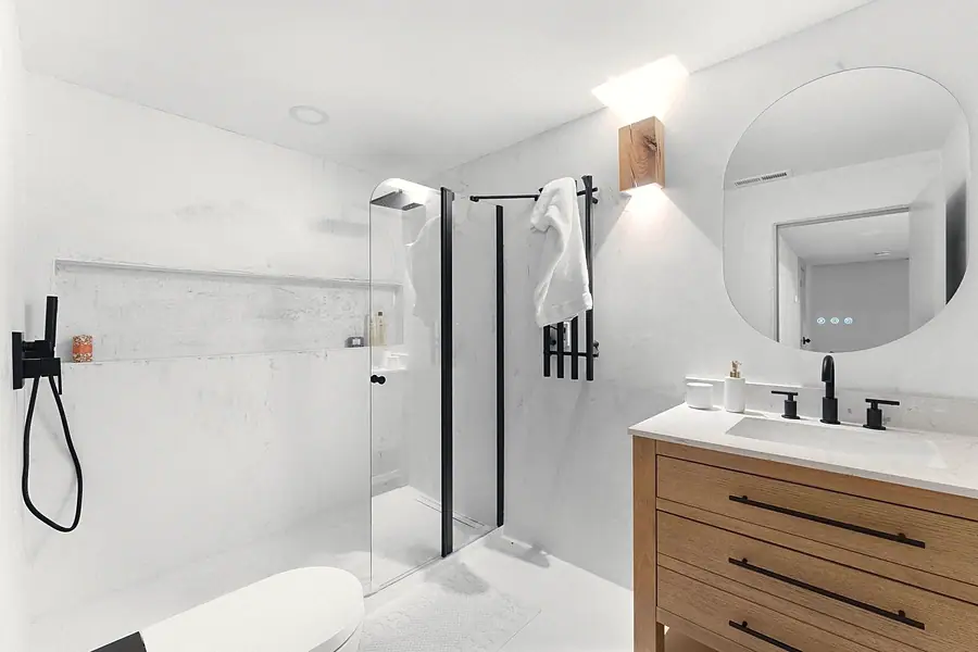 Little Gem marble bath with glass shower, wood vanity, and black fixtures