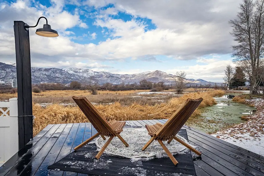 Wooden lounge chairs on the deck overlooking wetlands and snow-capped peaks