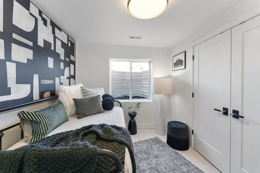 Guest bedroom with abstract wall art, daybed seating, and green knit throw