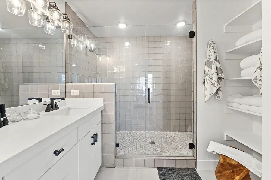 Silver Creek bath with walk-in glass shower, linen shelves, and white vanity