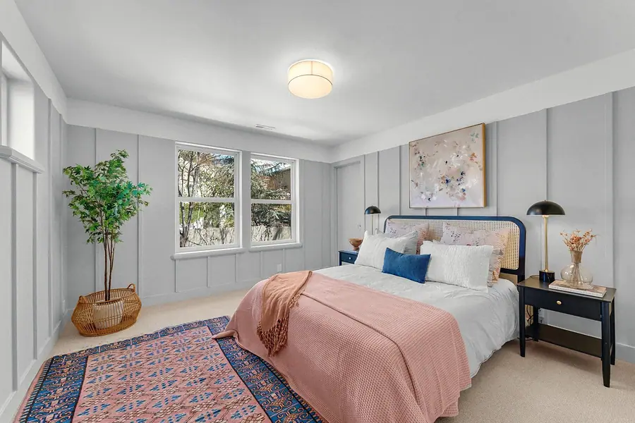 Grand Vista guest bedroom with cane headboard, blush throw, and patterned rug