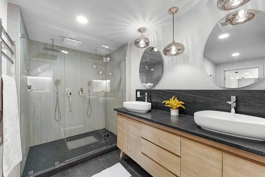 Grand Vista spa bath with glass shower, dual vessel sinks, and round mirrors