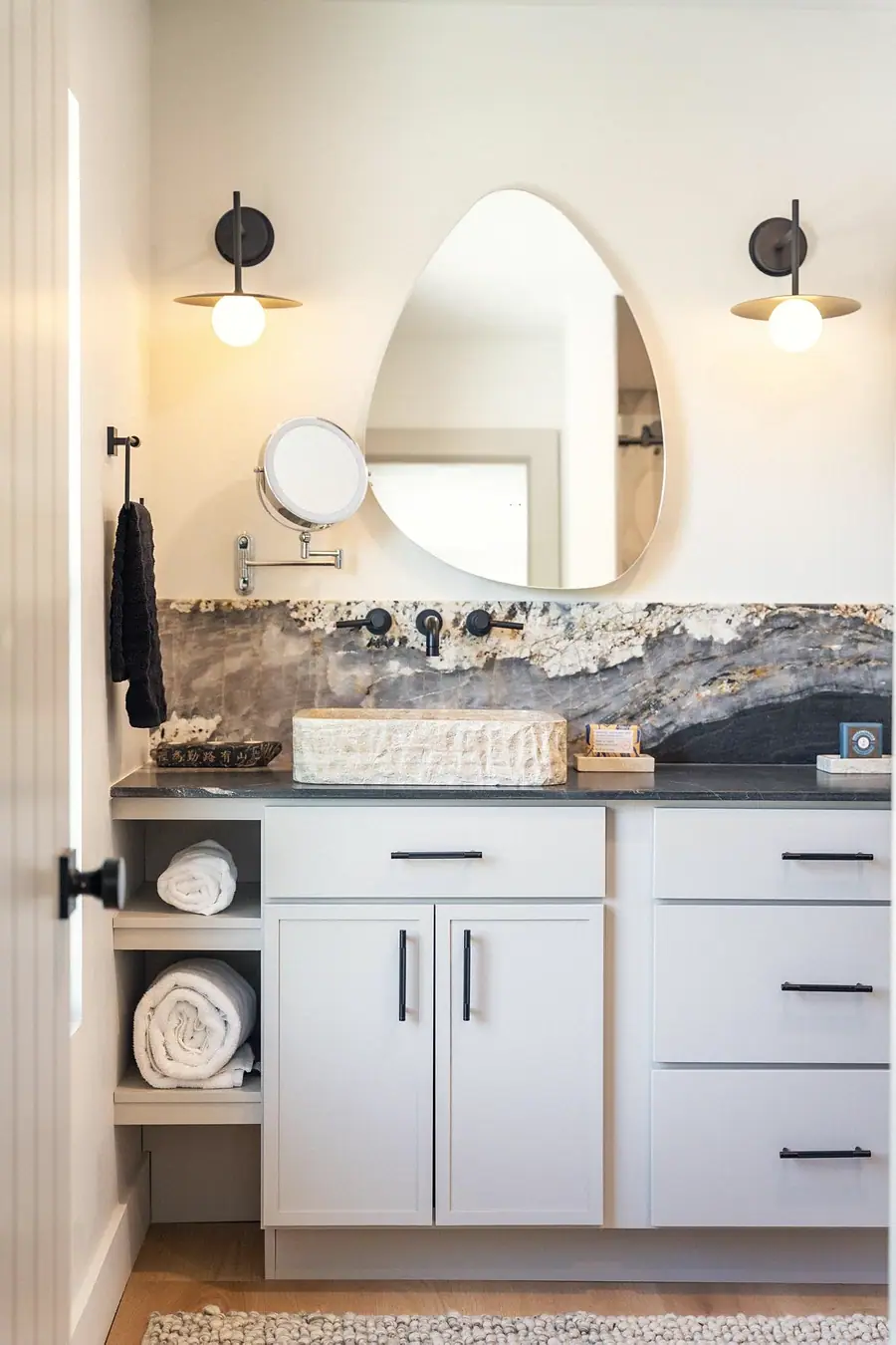 Little Gem primary bath with stone vessel sink, organic mirror, and marble backsplash