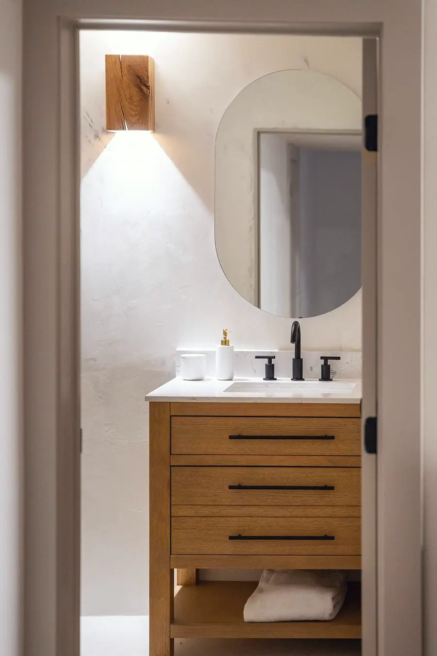Little Gem powder vanity with oval mirror, wood sconce, and oak drawers