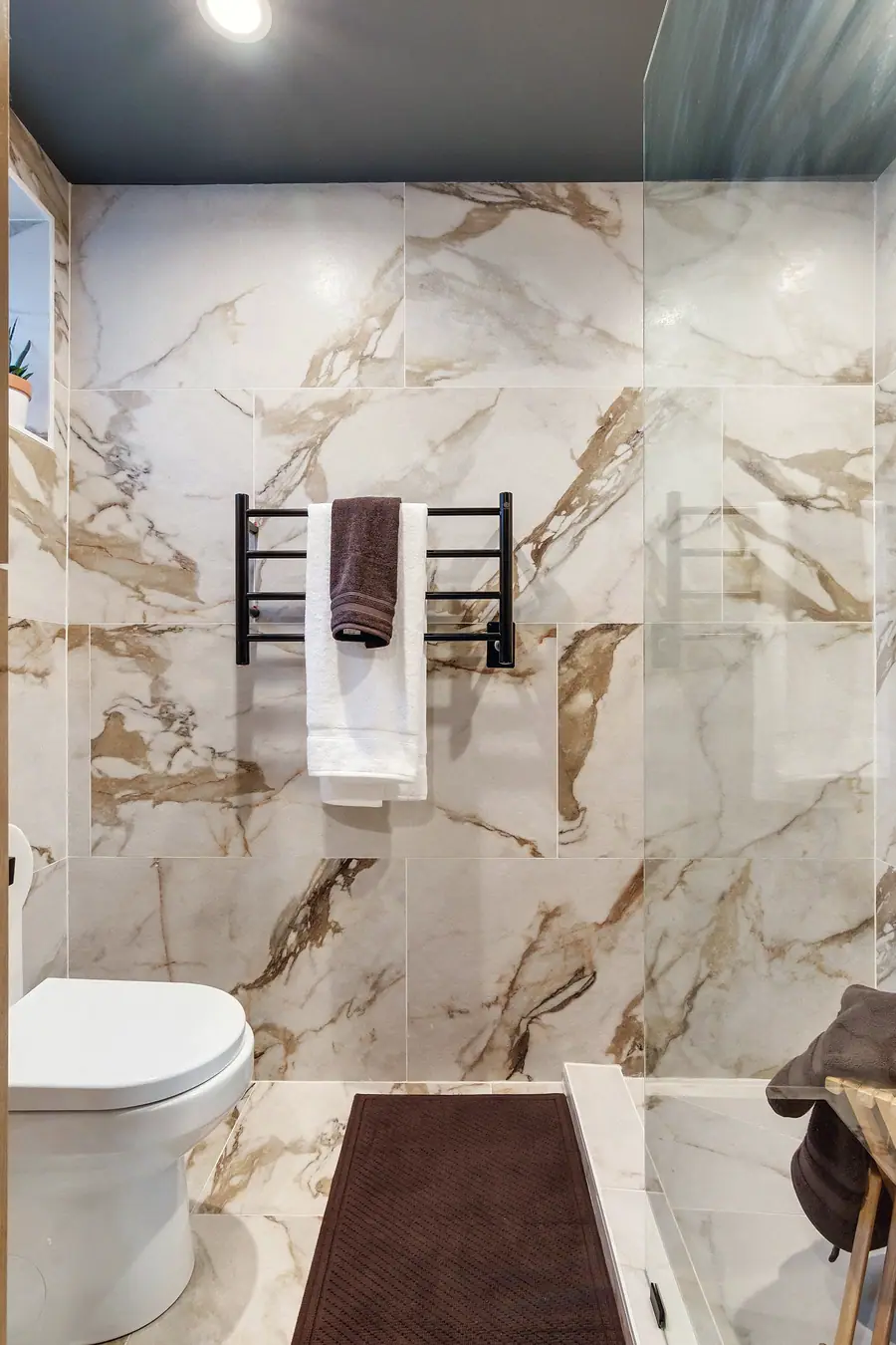 Wallace Project marble-tiled bathroom with heated towel rack and glass shower