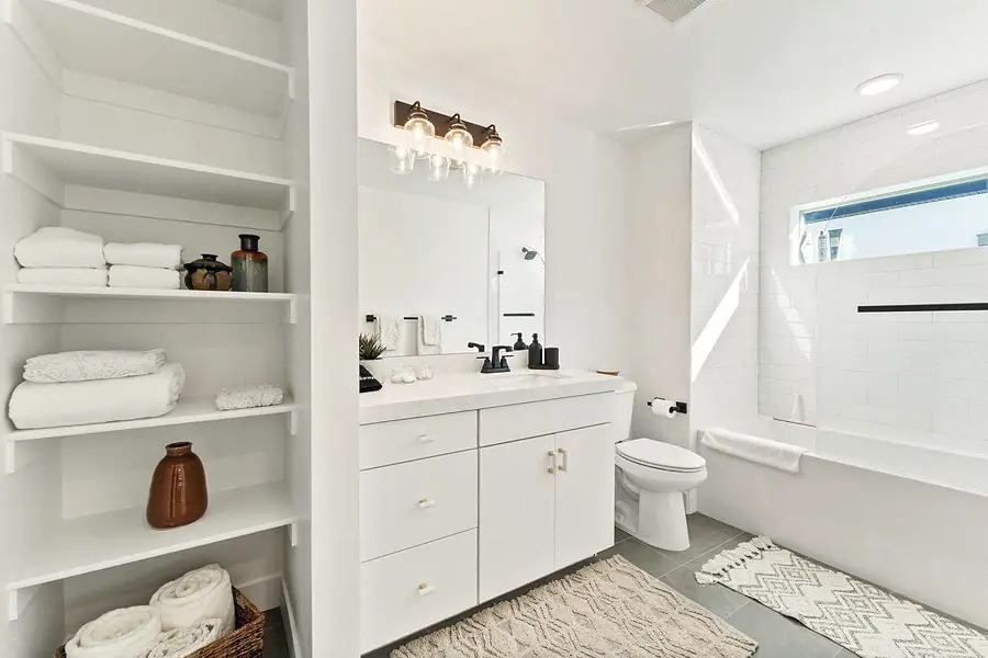 Silver Creek bath with open linen shelves, white vanity, and tub beyond